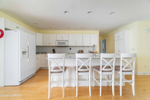 77 Indian Trl, Arapahoe, NC 28510 - kitchen featuring white appliances, a breakfast bar area, light wood-type flooring, light countertops, and recessed lighting