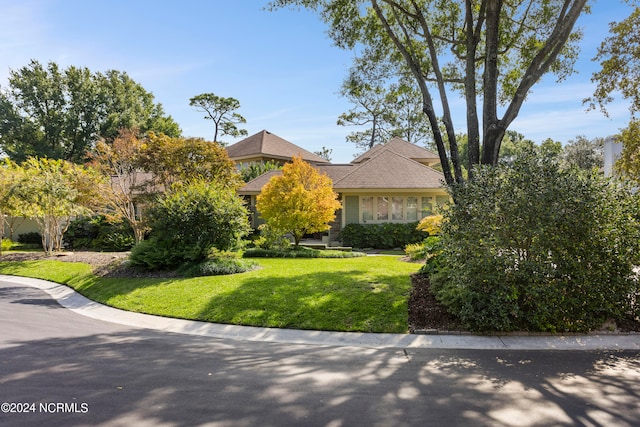 view of property hidden behind natural elements featuring a front yard