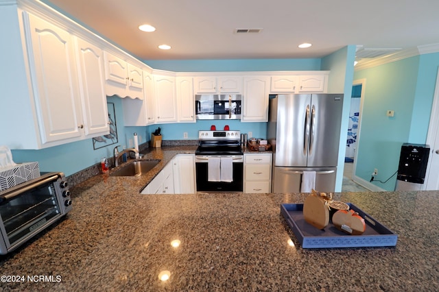 kitchen with white cabinets, sink, stainless steel appliances, dark stone counters, and crown molding