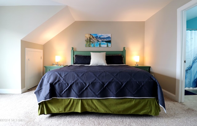 carpeted bedroom featuring lofted ceiling and ensuite bathroom