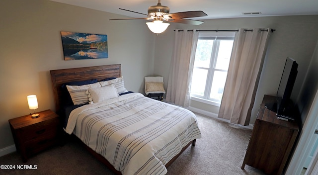 bedroom with dark colored carpet, multiple windows, and ceiling fan