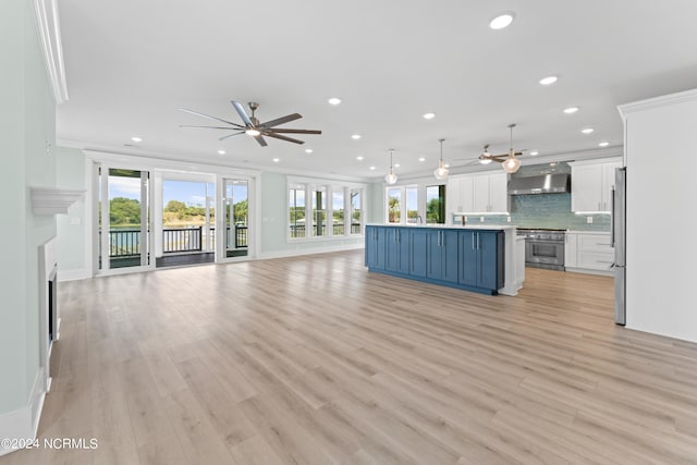 unfurnished living room featuring ceiling fan, light wood-type flooring, and crown molding