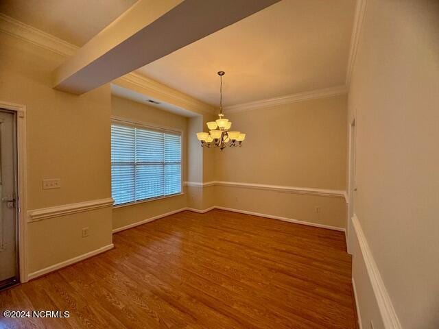 unfurnished dining area with hardwood / wood-style flooring, a notable chandelier, and crown molding