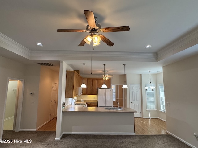 kitchen featuring kitchen peninsula, carpet floors, pendant lighting, white appliances, and a tray ceiling