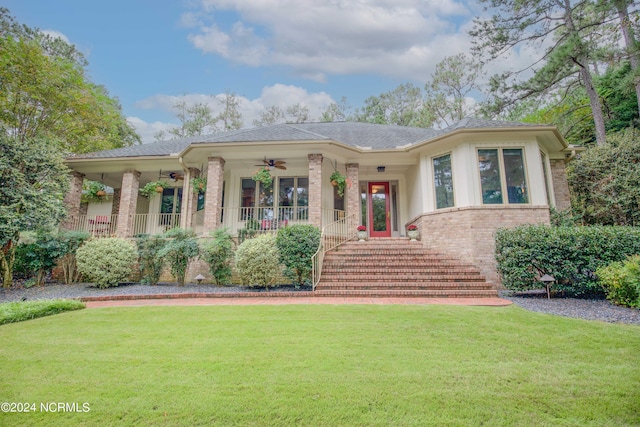 view of front facade with a ceiling fan, covered porch, stairs, a front lawn, and brick siding