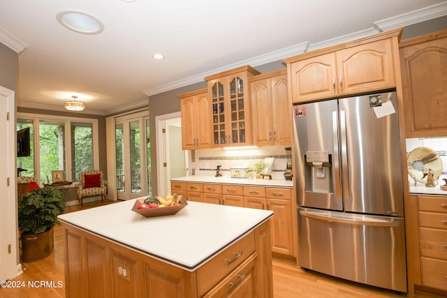 kitchen with light countertops, ornamental molding, tasteful backsplash, stainless steel fridge, and glass insert cabinets