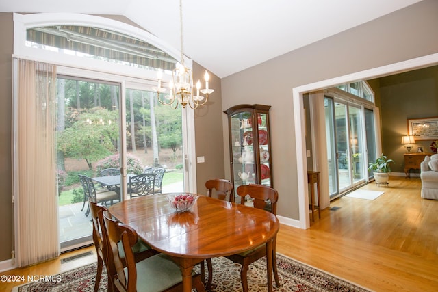 dining area featuring baseboards, visible vents, lofted ceiling, wood finished floors, and an inviting chandelier