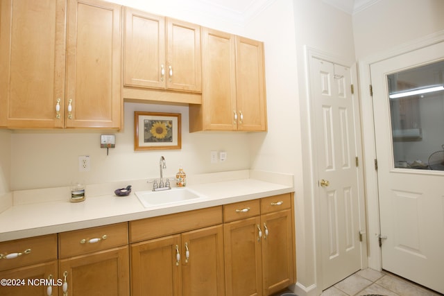 kitchen featuring light tile patterned floors, light countertops, ornamental molding, and a sink