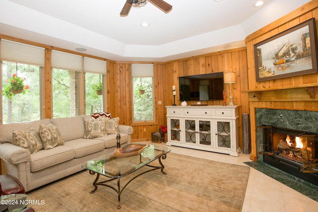 living room with a ceiling fan, a premium fireplace, tile patterned floors, wood walls, and recessed lighting