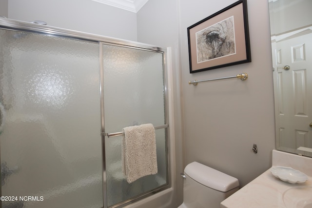 full bath featuring toilet, a shower with door, ornamental molding, and vanity