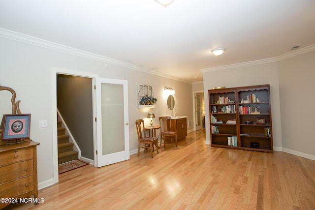 sitting room featuring light wood finished floors, stairs, baseboards, and crown molding