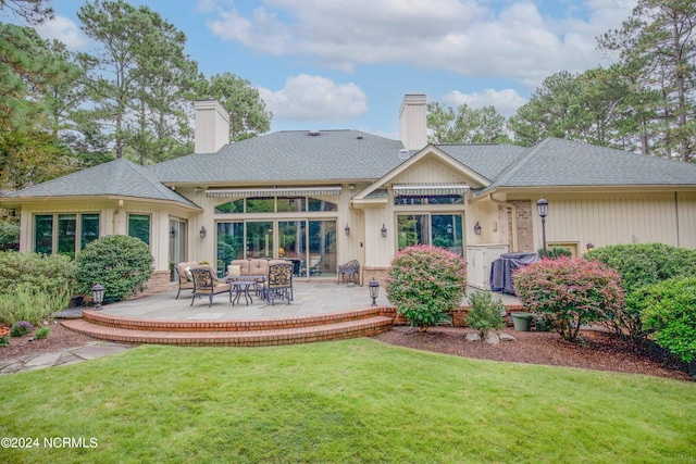 rear view of property with roof with shingles, a yard, a chimney, outdoor lounge area, and a patio area