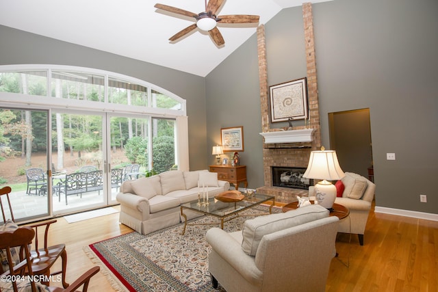 living area with a fireplace, light wood-style flooring, ceiling fan, high vaulted ceiling, and baseboards