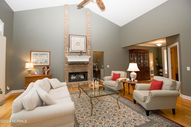 living room with light wood-style flooring, a fireplace, high vaulted ceiling, and baseboards