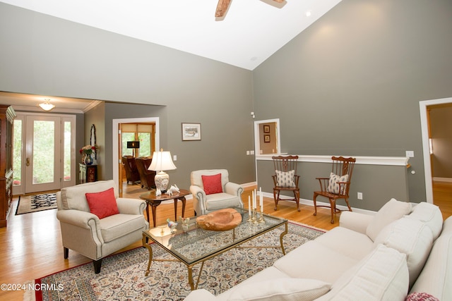 living area featuring light wood-type flooring, baseboards, high vaulted ceiling, and ceiling fan