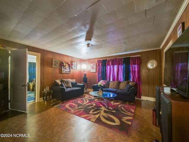 living room featuring crown molding, wood walls, ceiling fan, and dark parquet flooring