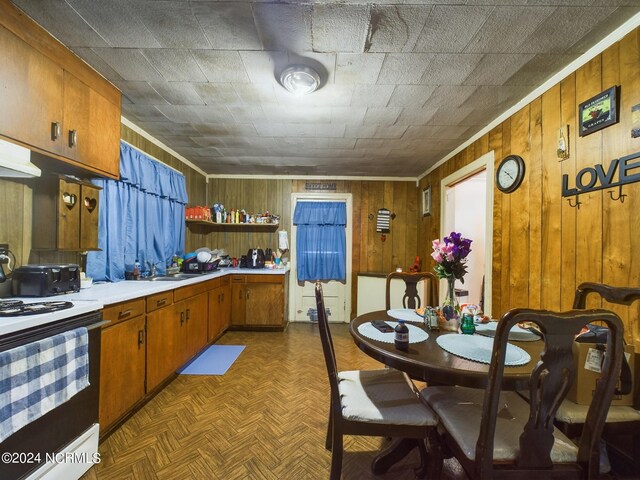 kitchen with parquet floors, wood walls, white electric range oven, and sink