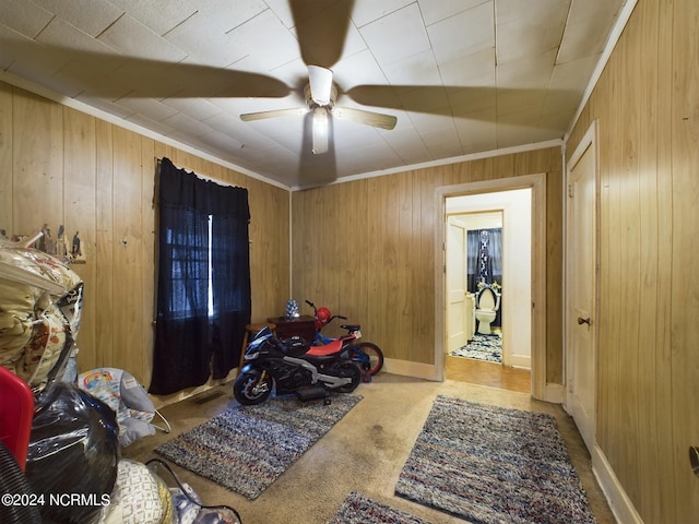 miscellaneous room with ornamental molding, wood walls, ceiling fan, and light colored carpet