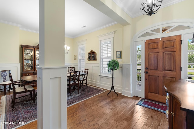 foyer with crown molding, dark wood-type flooring, and an inviting chandelier