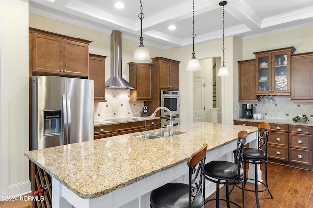 kitchen with pendant lighting, sink, stainless steel appliances, and wall chimney range hood