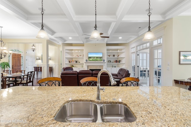 kitchen with beam ceiling, built in shelves, sink, coffered ceiling, and decorative light fixtures