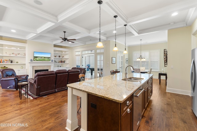 kitchen featuring coffered ceiling, a kitchen island with sink, sink, beam ceiling, and decorative light fixtures