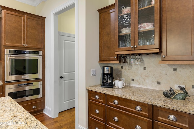 kitchen with light stone countertops, backsplash, and hardwood / wood-style flooring