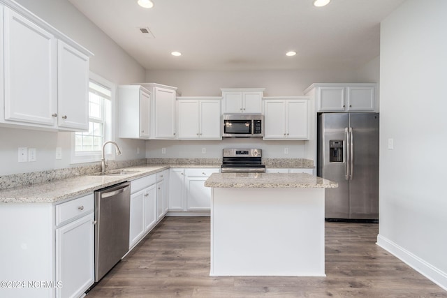 kitchen featuring white cabinets, appliances with stainless steel finishes, hardwood / wood-style flooring, and a kitchen island