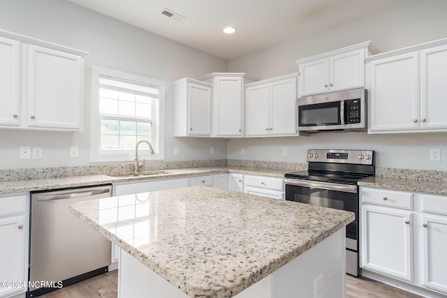 kitchen featuring light hardwood / wood-style floors, a kitchen island, stainless steel appliances, and white cabinets