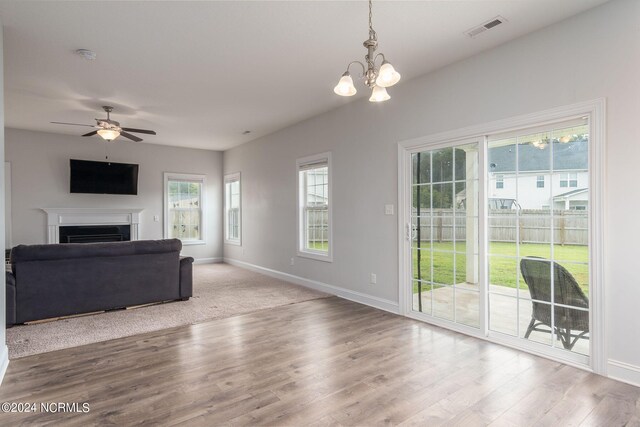 living room with ceiling fan with notable chandelier and light hardwood / wood-style floors