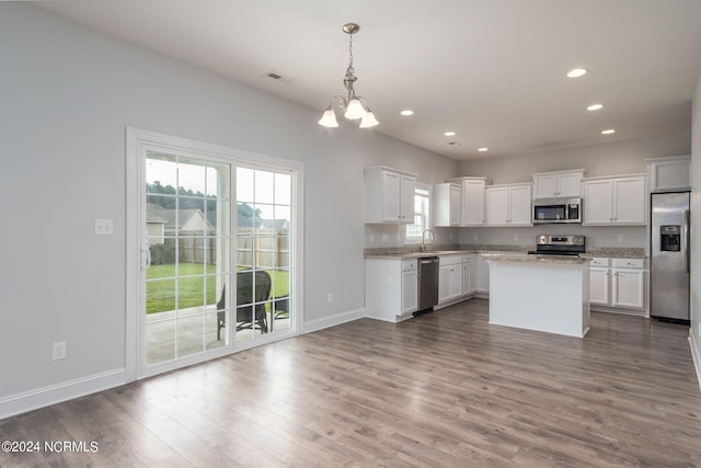 kitchen featuring white cabinetry, appliances with stainless steel finishes, decorative light fixtures, and a center island