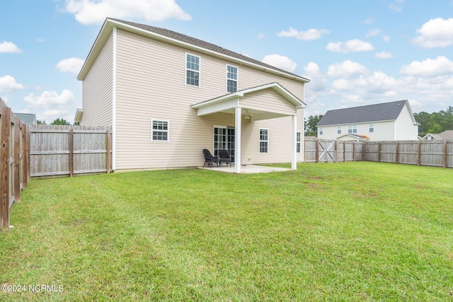 rear view of house featuring ceiling fan, a yard, and a patio