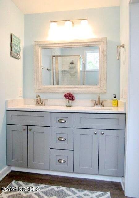 bathroom featuring wood-type flooring, a shower with door, and vanity