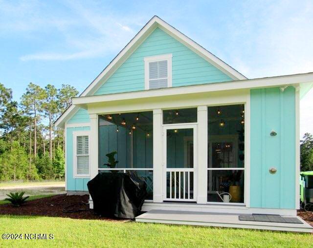 rear view of property featuring a sunroom and a lawn