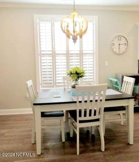 dining room with hardwood / wood-style flooring, crown molding, and a notable chandelier