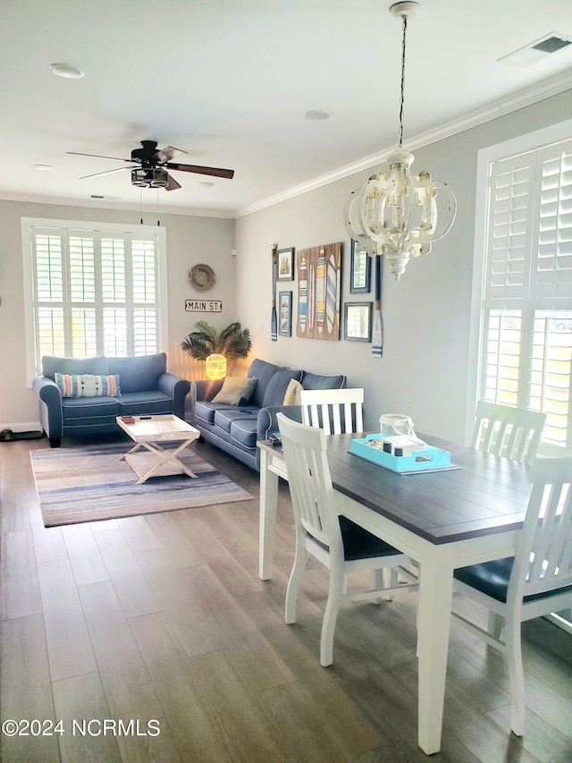 dining area featuring ornamental molding, ceiling fan with notable chandelier, and hardwood / wood-style floors