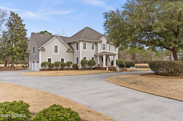 view of front of house with curved driveway, an attached garage, and roof with shingles