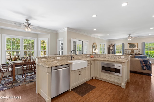 kitchen with sink, a kitchen island, stainless steel dishwasher, and light stone countertops