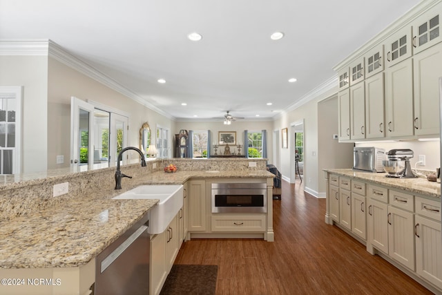 kitchen with a wealth of natural light, light stone countertops, sink, and stainless steel dishwasher