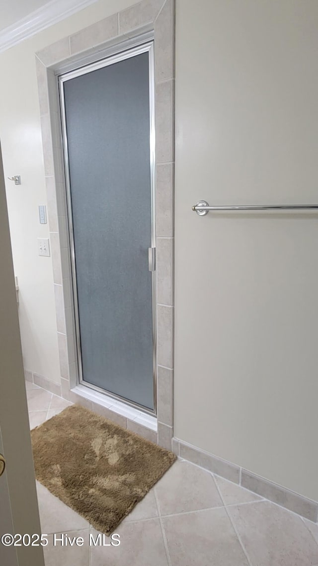 full bathroom with crown molding, tile patterned flooring, baseboards, and a stall shower