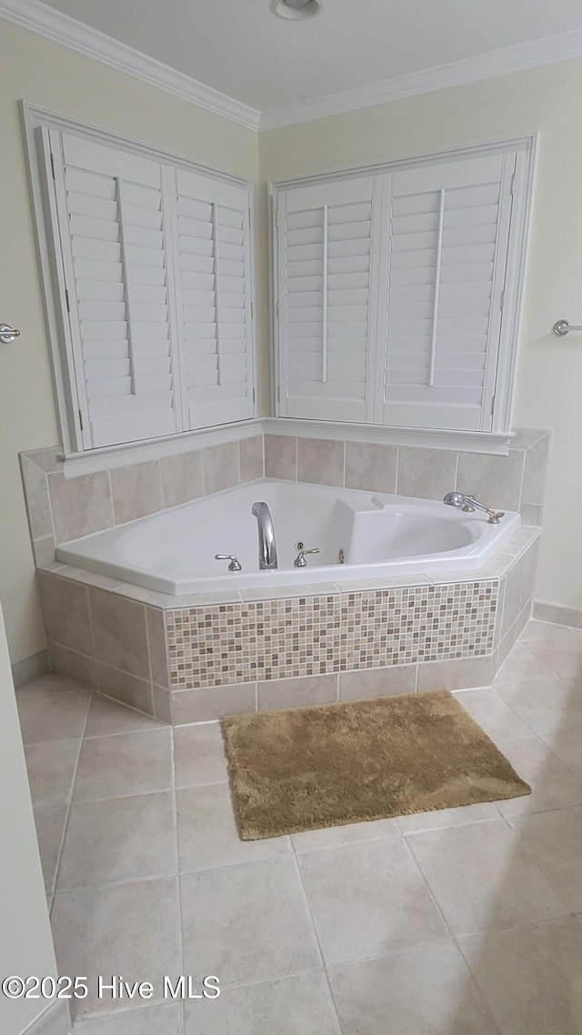 bathroom with tile patterned flooring, baseboards, ornamental molding, and a tub with jets
