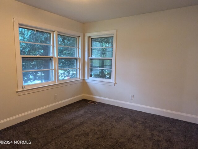 unfurnished room featuring dark carpet