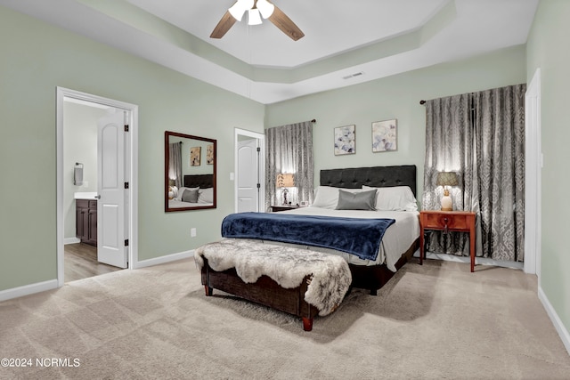 carpeted bedroom featuring ceiling fan, a tray ceiling, and connected bathroom