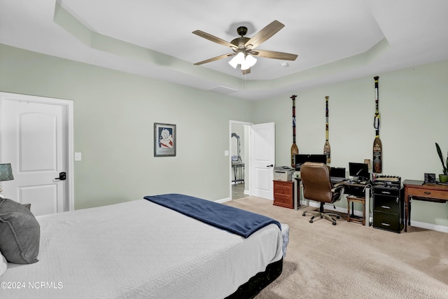 carpeted bedroom with a tray ceiling and ceiling fan