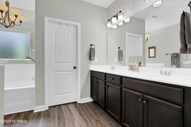 bathroom featuring an inviting chandelier, vanity, hardwood / wood-style floors, and a washtub