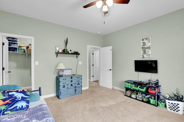 carpeted bedroom with a spacious closet, ceiling fan, and a closet