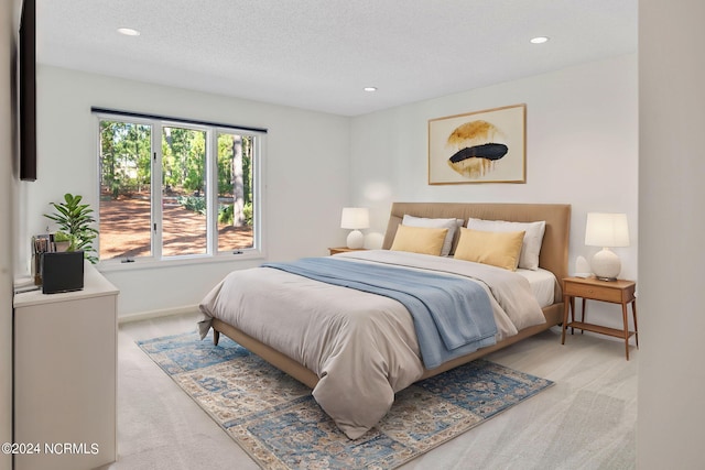 bedroom with a textured ceiling and light colored carpet