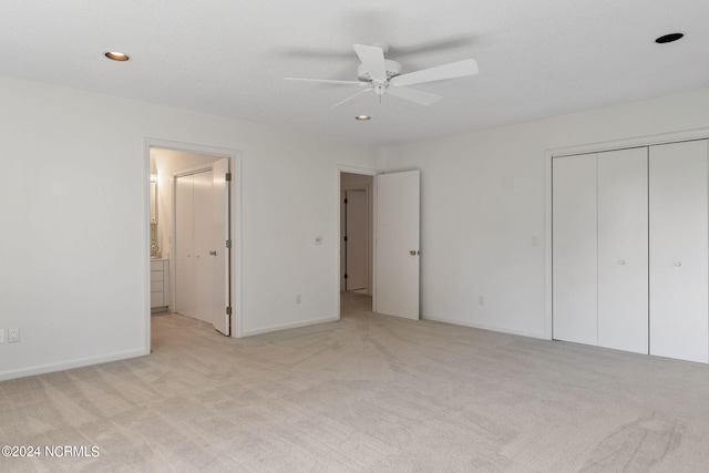 unfurnished bedroom featuring light carpet, connected bathroom, a closet, and ceiling fan