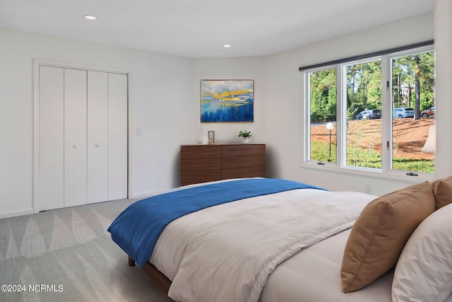 bedroom featuring light carpet, a textured ceiling, and a closet