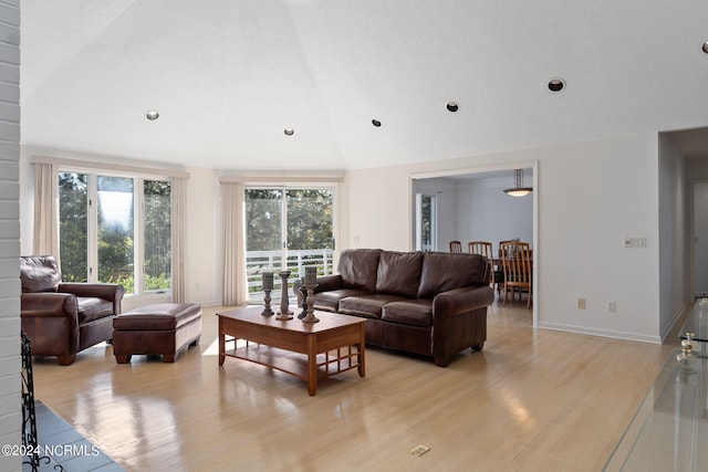 living room featuring light wood-type flooring, vaulted ceiling, and a textured ceiling